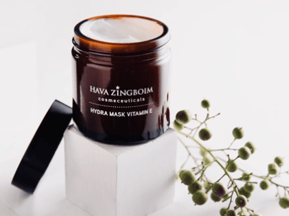 מסכת Hydra Mask Vitamin E של חוה זינגבוים על רקע לבן עם צמח ירוק